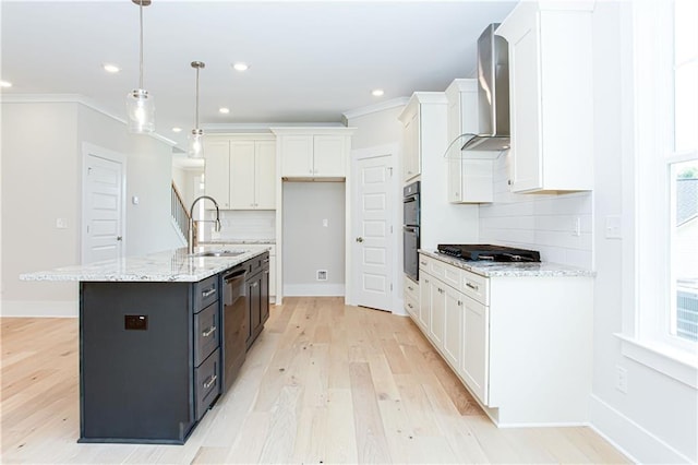 kitchen featuring a sink, appliances with stainless steel finishes, white cabinetry, crown molding, and wall chimney exhaust hood