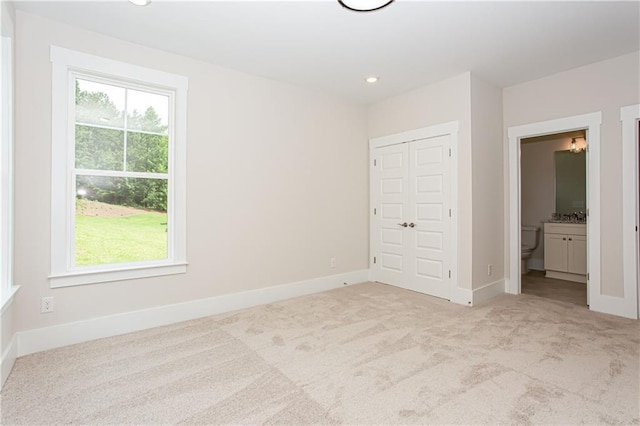 unfurnished bedroom featuring multiple windows, carpet flooring, and baseboards