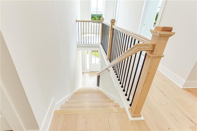 stairs with a towering ceiling, baseboards, and wood finished floors