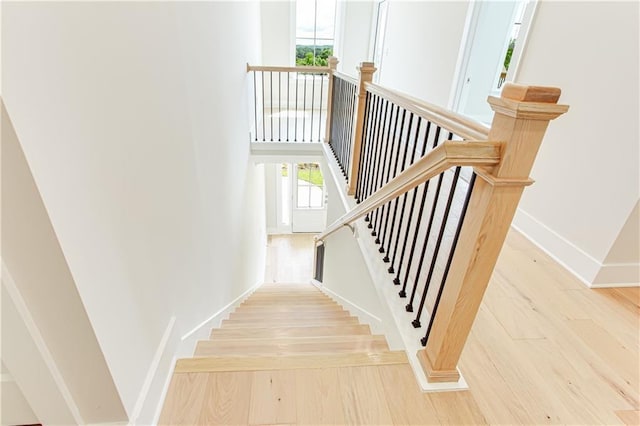 stairway with hardwood / wood-style floors and a high ceiling