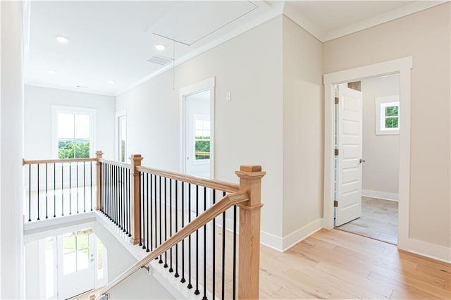 hallway with wood finished floors, an upstairs landing, attic access, and ornamental molding