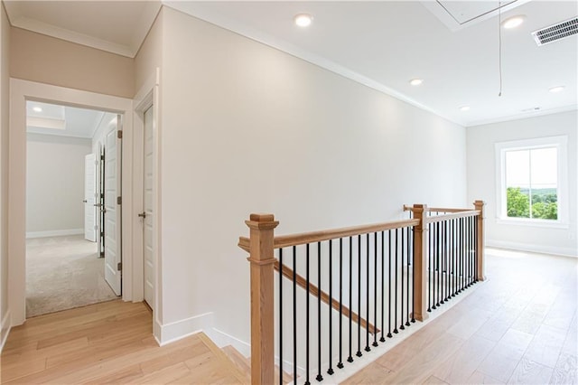 hall featuring visible vents, an upstairs landing, ornamental molding, light wood finished floors, and attic access