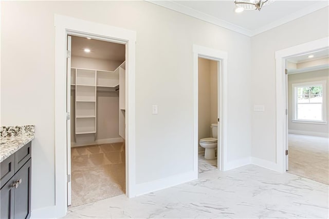 interior space with toilet, baseboards, marble finish floor, and ornamental molding