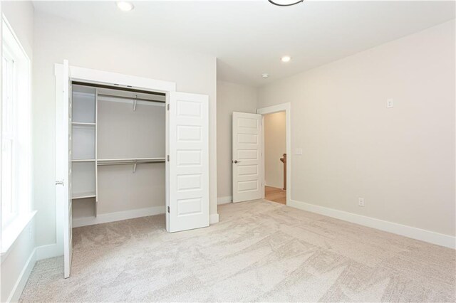 unfurnished bedroom featuring recessed lighting, a closet, carpet floors, and baseboards