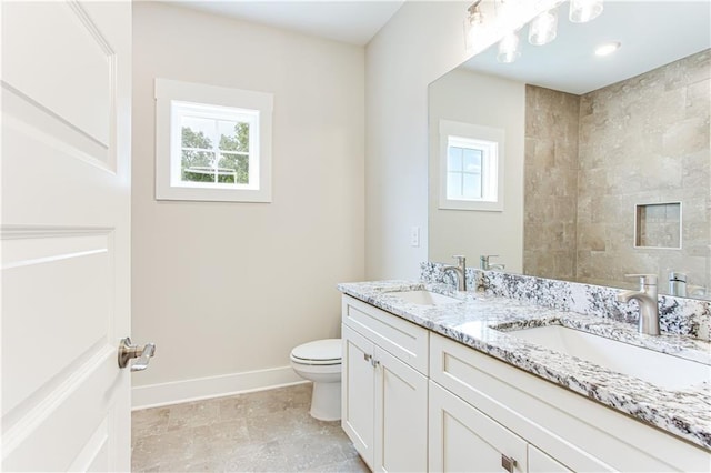 full bath with a sink, baseboards, toilet, and double vanity