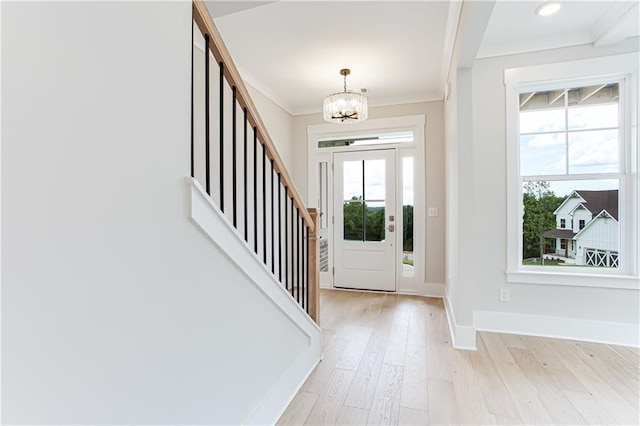 entryway with light wood-style flooring, stairway, an inviting chandelier, crown molding, and baseboards