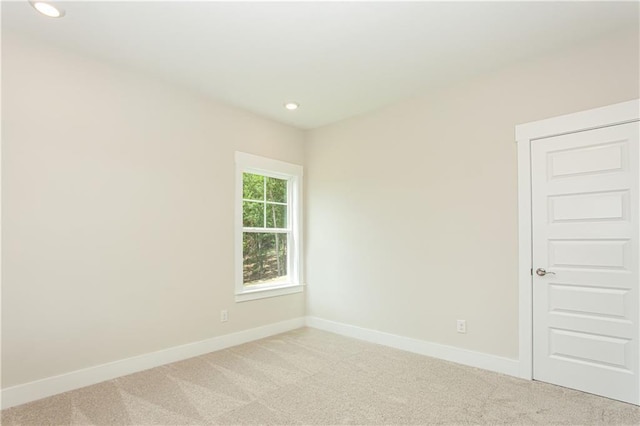 empty room featuring recessed lighting, baseboards, and light colored carpet