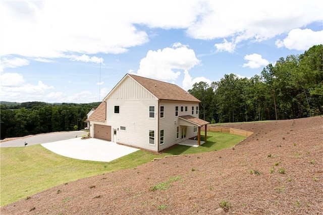 rear view of house with a lawn, board and batten siding, concrete driveway, and a garage