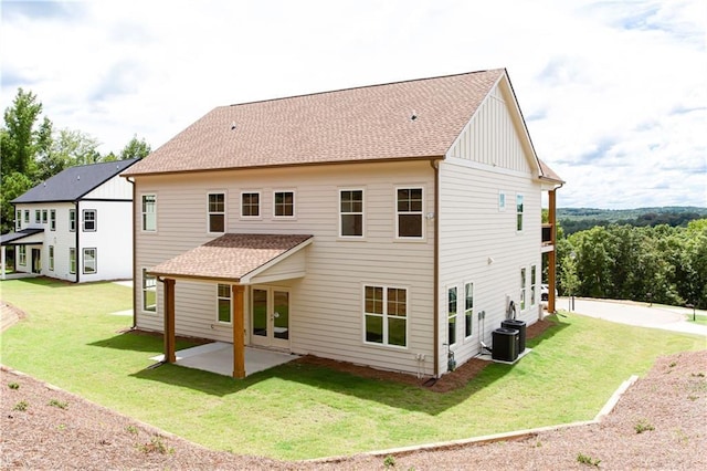 back of house with a patio, a yard, central AC, a shingled roof, and board and batten siding