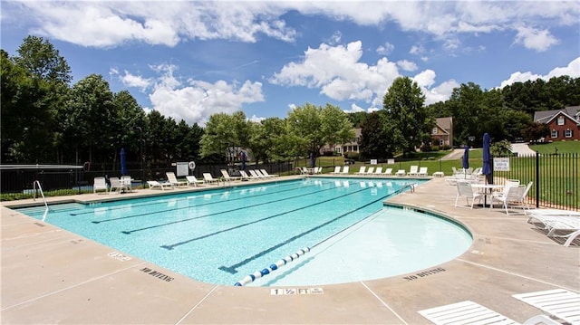 community pool with a patio area and fence