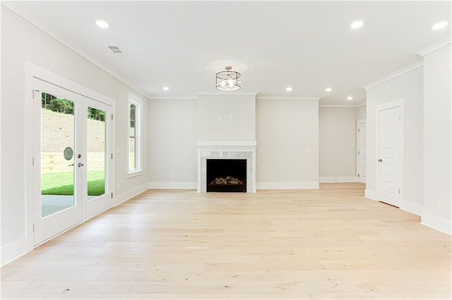 unfurnished living room featuring french doors, a high end fireplace, crown molding, and light wood-type flooring