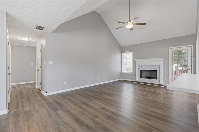 unfurnished living room with ceiling fan, dark hardwood / wood-style floors, a fireplace, a textured ceiling, and vaulted ceiling