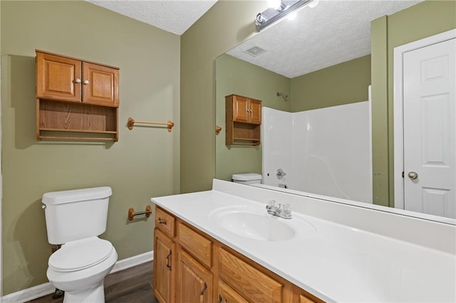 bathroom with vanity, toilet, hardwood / wood-style floors, and a textured ceiling