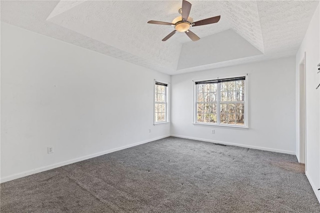 carpeted empty room with ceiling fan, a tray ceiling, and a textured ceiling