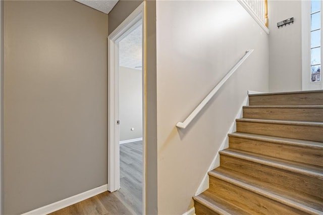 stairway with hardwood / wood-style floors and a textured ceiling