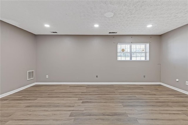 spare room with light hardwood / wood-style floors and a textured ceiling