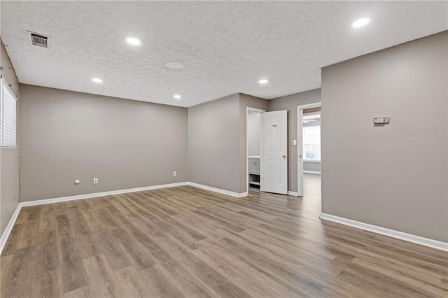 spare room featuring a textured ceiling and light wood-type flooring