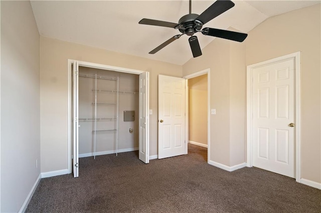 unfurnished bedroom with lofted ceiling, baseboards, dark colored carpet, and a closet