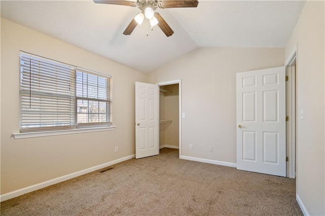 unfurnished bedroom with lofted ceiling, light carpet, visible vents, baseboards, and a spacious closet