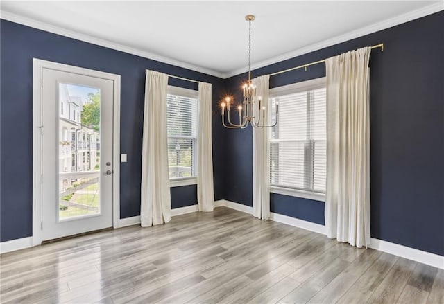 spare room featuring a notable chandelier, ornamental molding, and light hardwood / wood-style floors