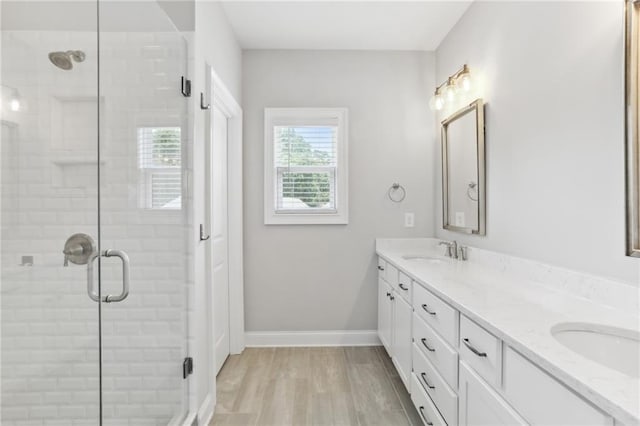 bathroom with a shower with door, double vanity, and hardwood / wood-style flooring