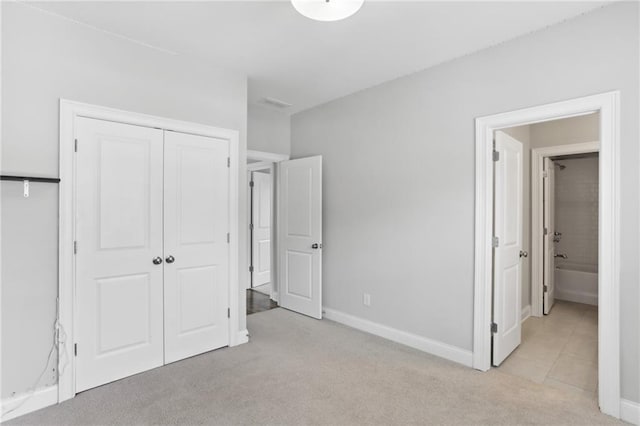 unfurnished bedroom featuring a closet, light carpet, and connected bathroom