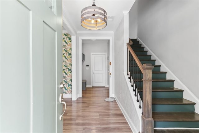 entryway featuring crown molding, a chandelier, and light wood-type flooring