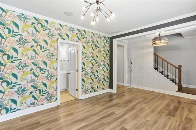 spare room featuring an inviting chandelier, crown molding, and light hardwood / wood-style floors