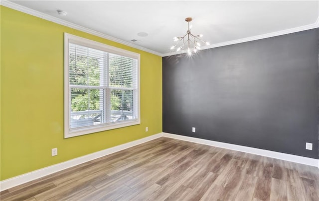 spare room featuring light hardwood / wood-style flooring, ornamental molding, a chandelier, and plenty of natural light