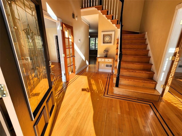 stairs featuring a towering ceiling and wood-type flooring