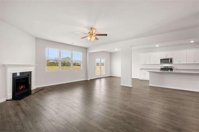 5430 Flat Rock Pt, Stonecrest, GA 30038 - unfurnished living room with ceiling fan, dark wood-style flooring, a lit fireplace, and baseboards