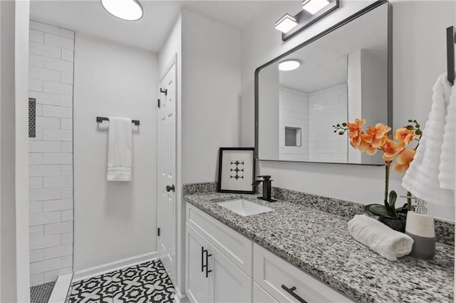 bathroom with tiled shower, vanity, and tile patterned flooring