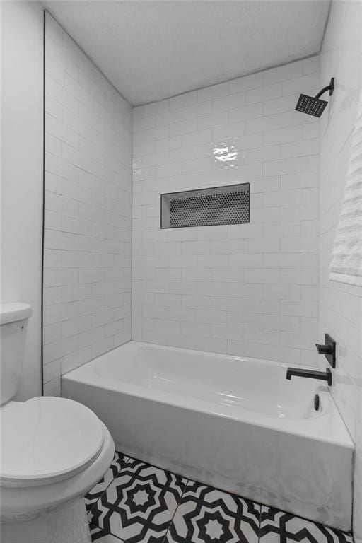 bathroom with tiled shower / bath combo and toilet