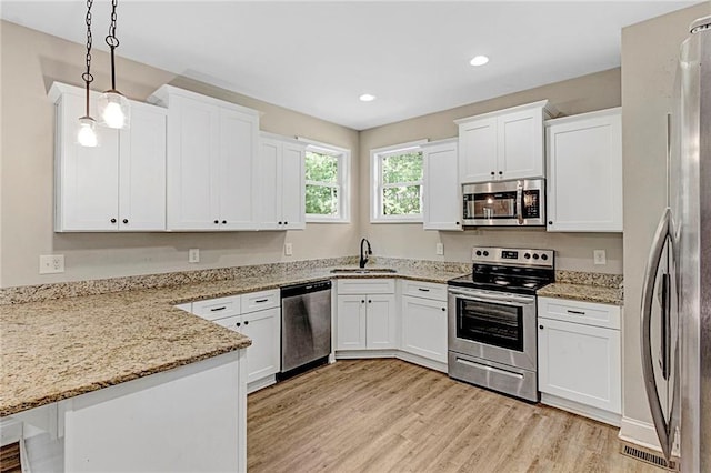 kitchen featuring appliances with stainless steel finishes, a sink, a peninsula, white cabinets, and recessed lighting