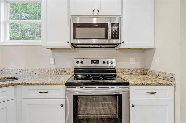 kitchen featuring appliances with stainless steel finishes, white cabinetry, and light stone countertops