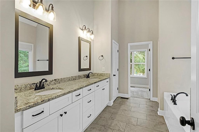 bathroom with double vanity, baseboards, a garden tub, and a high ceiling