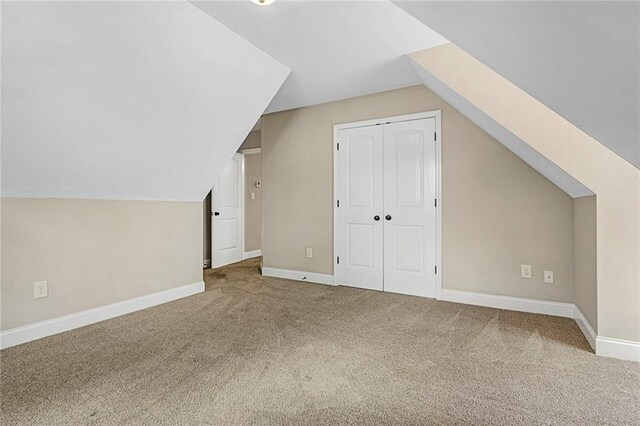 additional living space featuring carpet, vaulted ceiling, and baseboards