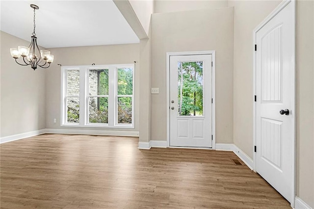 foyer entrance with wood finished floors, a chandelier, and baseboards