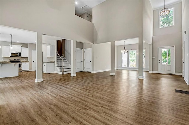 unfurnished living room featuring a high ceiling, wood finished floors, healthy amount of natural light, and baseboards