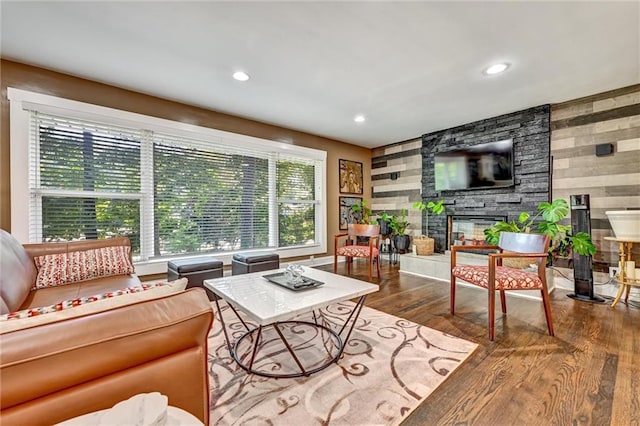 living area featuring recessed lighting, a fireplace, wood walls, and wood finished floors