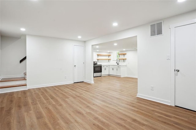 unfurnished living room with visible vents, light wood-type flooring, stairs, and recessed lighting