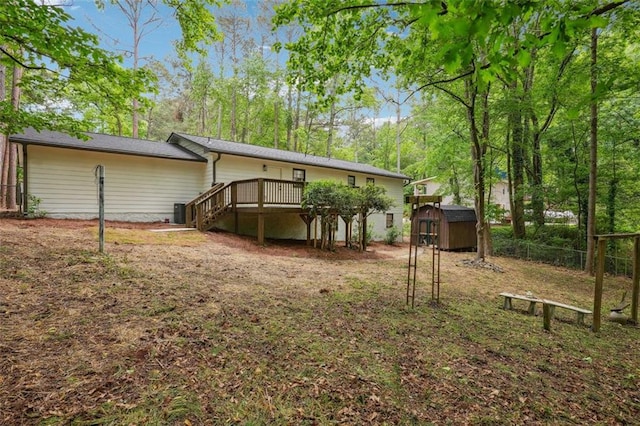 rear view of property with a storage unit, a deck, an outbuilding, fence, and stairway