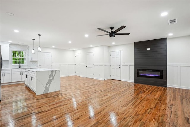kitchen with a ceiling fan, visible vents, light wood-style flooring, and a decorative wall