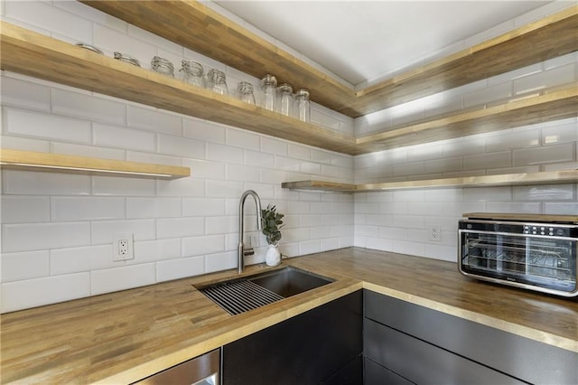 kitchen with butcher block counters, sink, and decorative backsplash