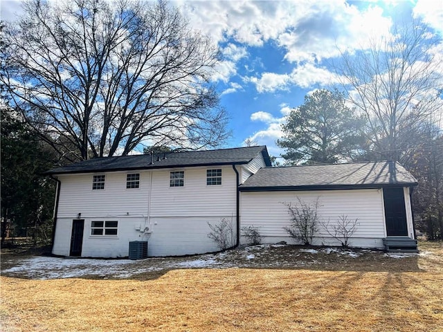 rear view of house with cooling unit and a yard