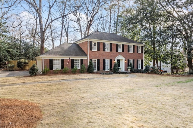 colonial home with a front yard, fence, and brick siding