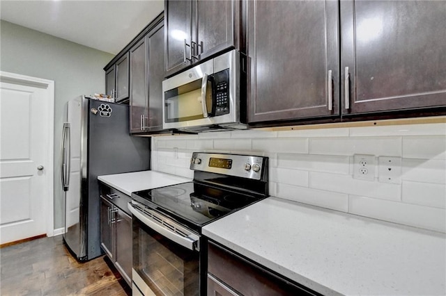 kitchen with appliances with stainless steel finishes, wood finished floors, dark brown cabinetry, and tasteful backsplash