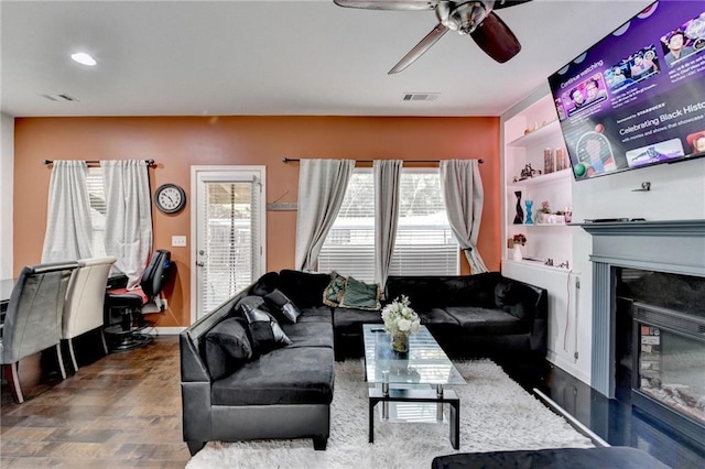 living area with plenty of natural light, visible vents, wood finished floors, and a glass covered fireplace