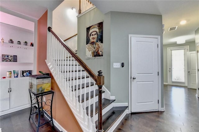 staircase featuring baseboards, visible vents, and wood finished floors