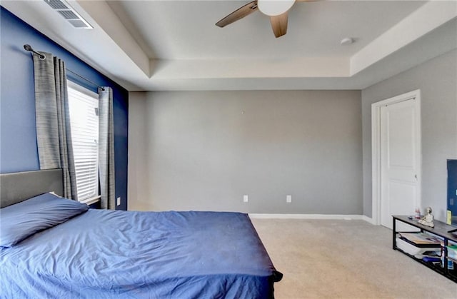 bedroom with light carpet, a raised ceiling, visible vents, and baseboards